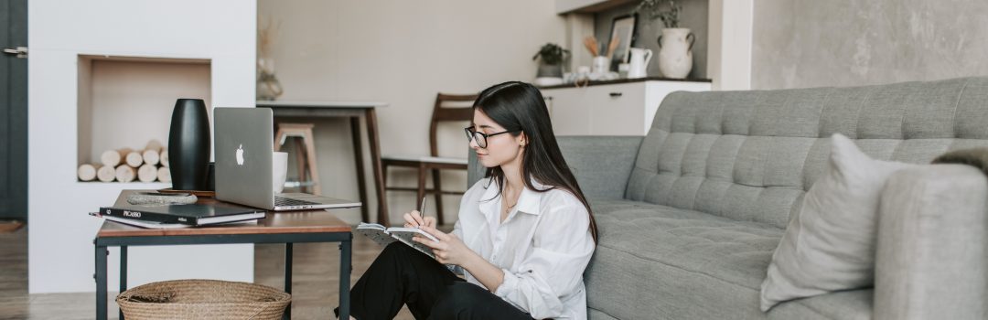 girl sitting on floor in front of couch using laptop